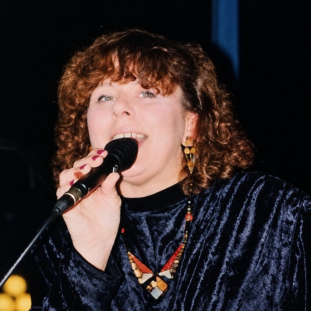Christine Emmert singt mit Mikrofon auf der Bühne